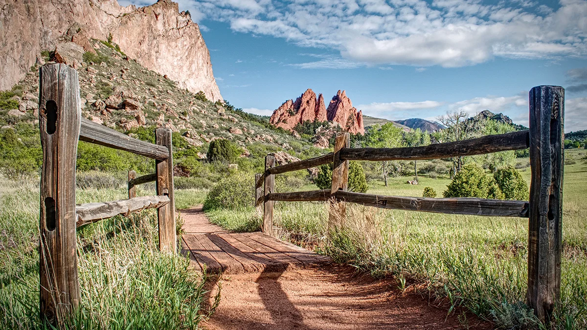 co_springs_353387420 Wood fence frames a hiking trail which leads towards interesting rock formations in Garden of the Gods Park in Colorado Springs.